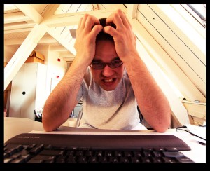 A frustrated man pulls his hair over a computer screen